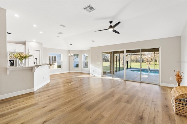 unfurnished living room featuring ceiling fan, light hardwood / wood-style flooring, sink, and lofted ceiling