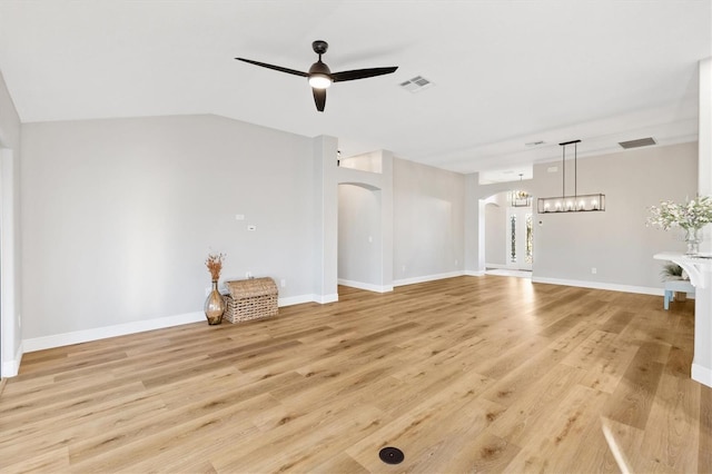 unfurnished living room featuring ceiling fan with notable chandelier, light wood-type flooring, and lofted ceiling