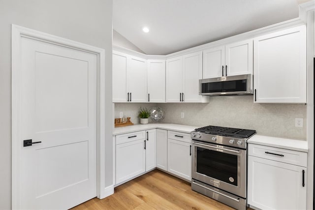 kitchen with appliances with stainless steel finishes, decorative backsplash, light hardwood / wood-style floors, and white cabinetry