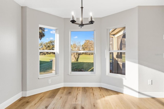 unfurnished dining area featuring a chandelier and light hardwood / wood-style floors