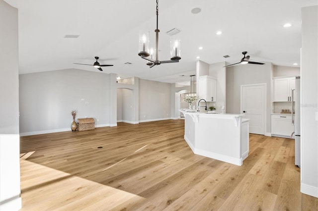 kitchen featuring white cabinets, hanging light fixtures, lofted ceiling, and ceiling fan with notable chandelier