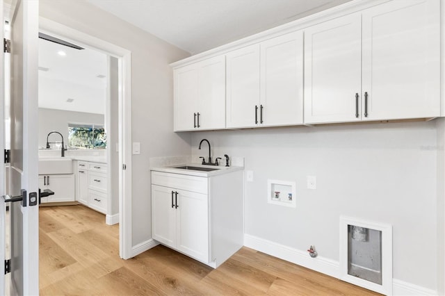 washroom with sink, washer hookup, cabinets, and light hardwood / wood-style floors