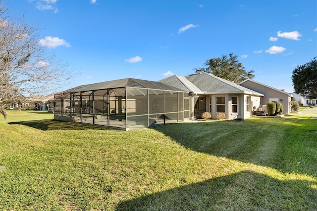 back of property with a yard, glass enclosure, and a patio