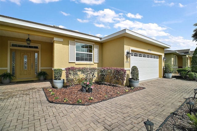 single story home featuring a garage, decorative driveway, and stucco siding