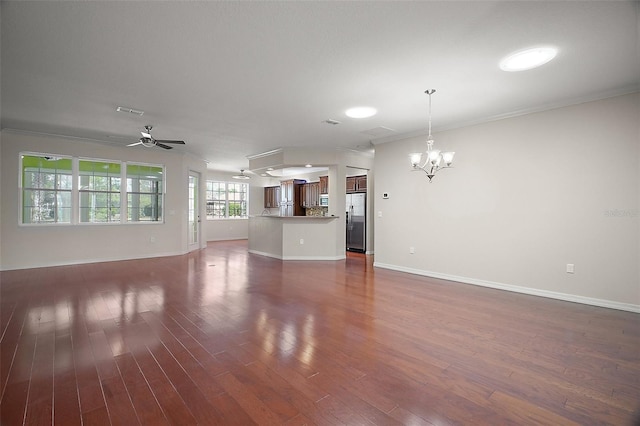 unfurnished living room with baseboards, visible vents, dark wood-type flooring, crown molding, and ceiling fan with notable chandelier