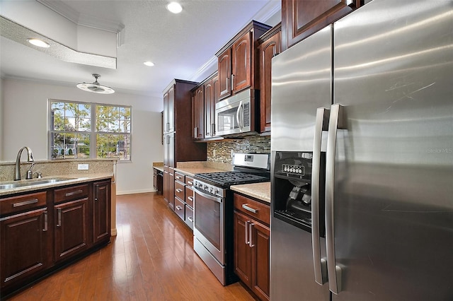 kitchen with crown molding, stainless steel appliances, backsplash, dark wood-type flooring, and a sink