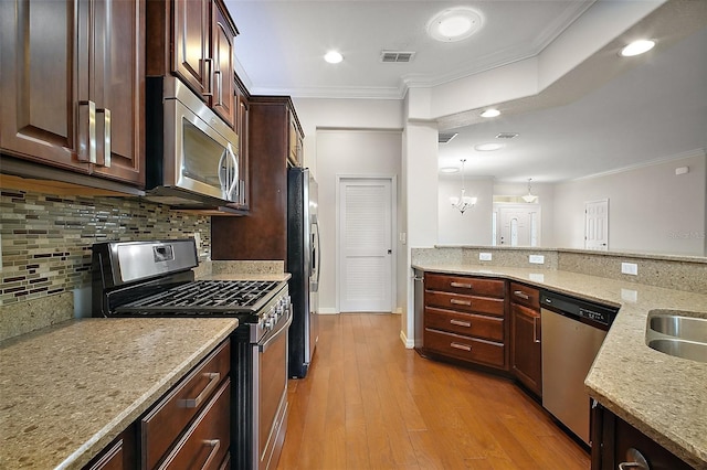 kitchen featuring appliances with stainless steel finishes, light wood-type flooring, visible vents, and crown molding