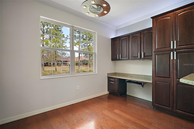 unfurnished office with baseboards, dark wood-type flooring, built in study area, and crown molding