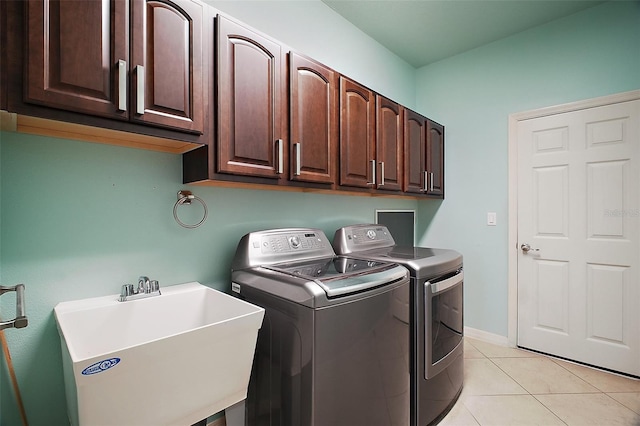 laundry area with light tile patterned flooring, a sink, baseboards, independent washer and dryer, and cabinet space