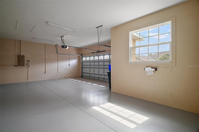 garage with a garage door opener, concrete block wall, and electric panel