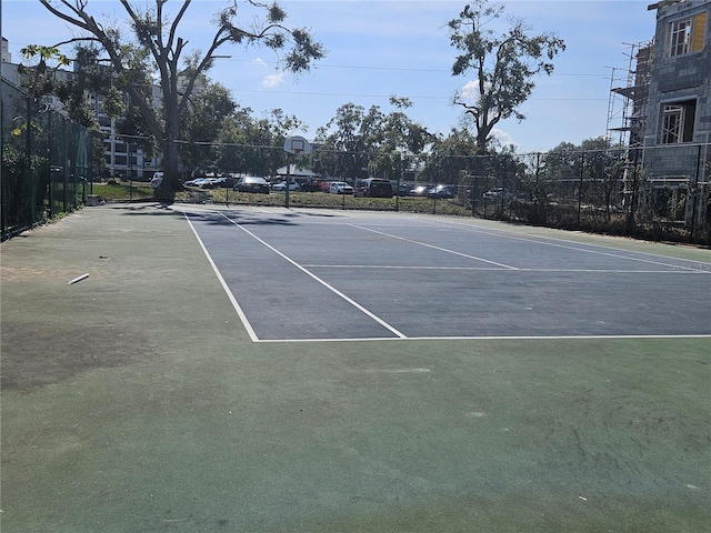 view of tennis court featuring community basketball court and fence