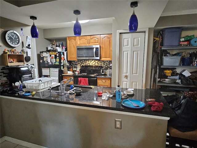 kitchen featuring a sink, decorative backsplash, black appliances, dark stone countertops, and decorative light fixtures