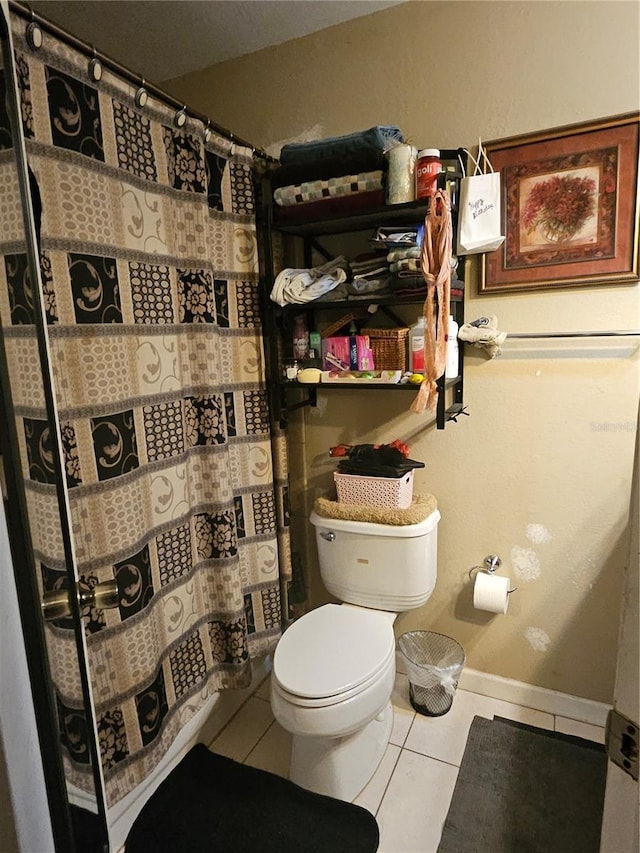 full bath featuring baseboards, a shower with curtain, toilet, and tile patterned floors