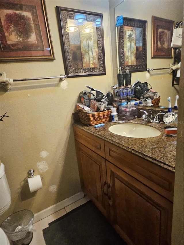 half bathroom with baseboards, vanity, toilet, and tile patterned floors