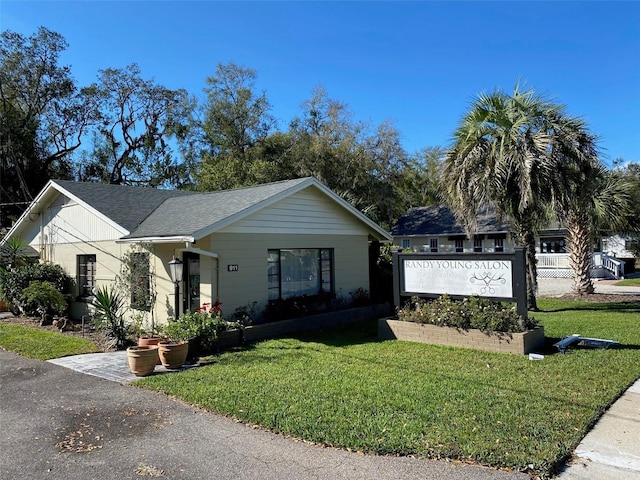 view of front of property with roof with shingles and a front yard