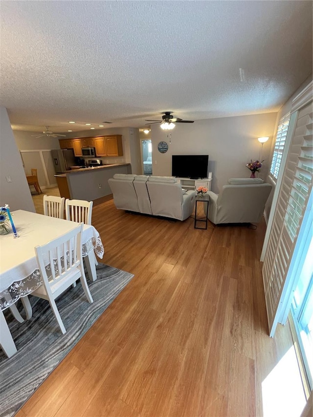 dining room with ceiling fan, a textured ceiling, and light hardwood / wood-style floors