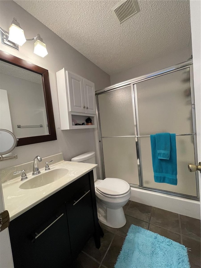 bathroom with tile patterned flooring, toilet, a textured ceiling, an enclosed shower, and vanity