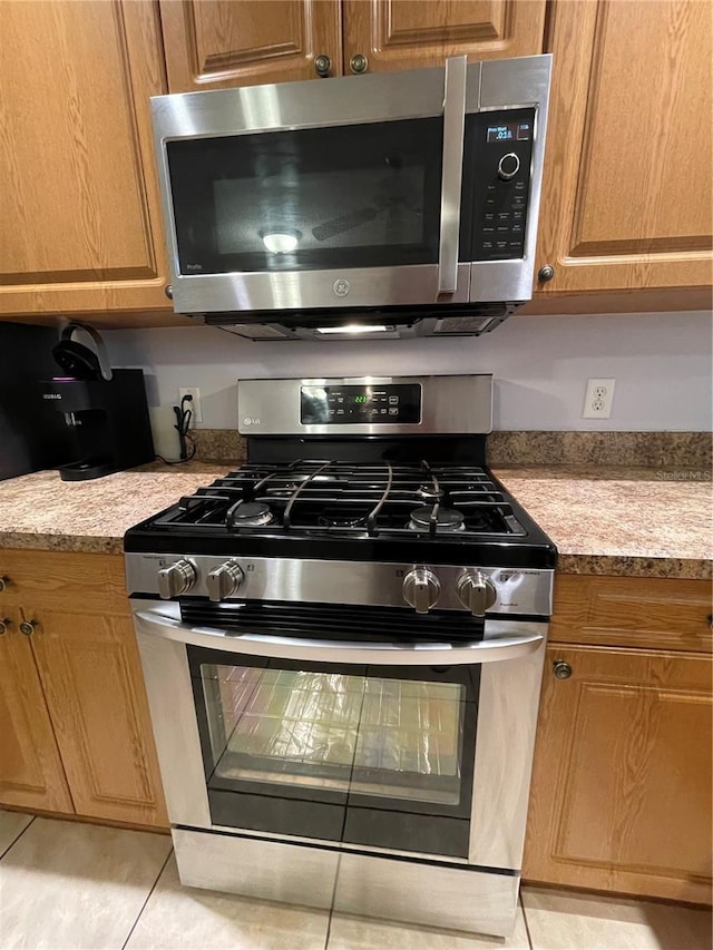 kitchen with appliances with stainless steel finishes, light stone counters, and light tile patterned floors