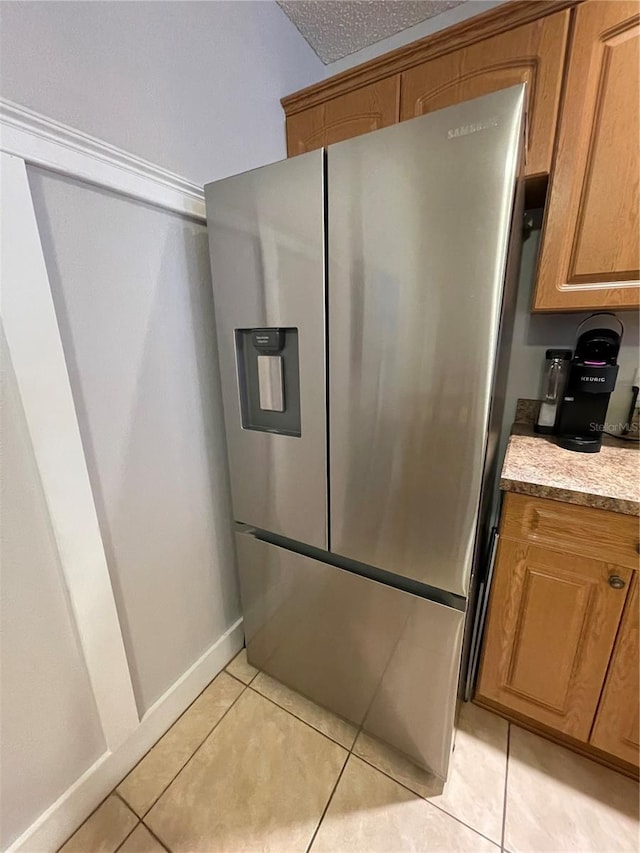 kitchen with light tile patterned flooring and stainless steel fridge