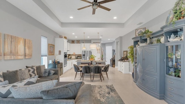 living area with a ceiling fan, recessed lighting, a raised ceiling, and visible vents