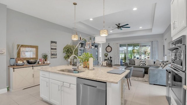 kitchen featuring a raised ceiling, stainless steel appliances, open floor plan, and a sink