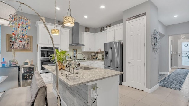 kitchen featuring white cabinets, wine cooler, appliances with stainless steel finishes, light stone countertops, and wall chimney range hood