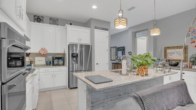 kitchen with stainless steel appliances, hanging light fixtures, white cabinetry, and light stone counters