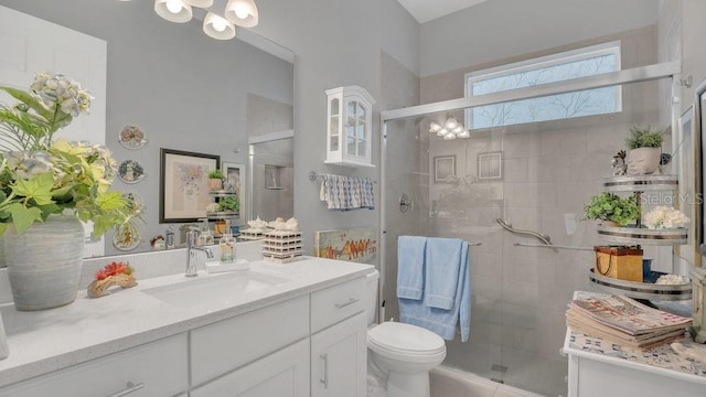 full bath with a stall shower, vanity, toilet, and a notable chandelier