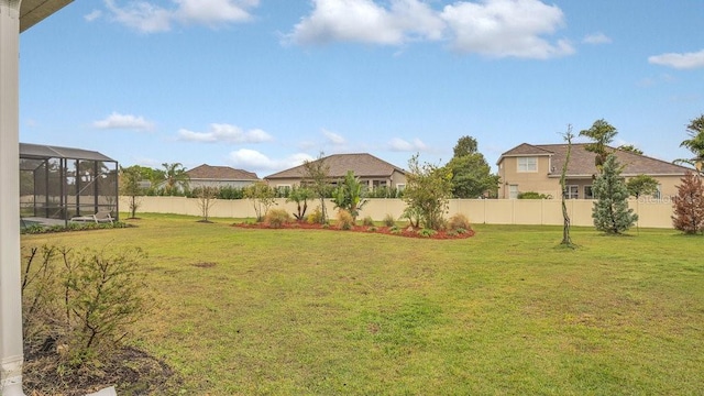 view of yard with glass enclosure and a fenced backyard