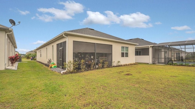 rear view of house with a lawn, a lanai, and stucco siding