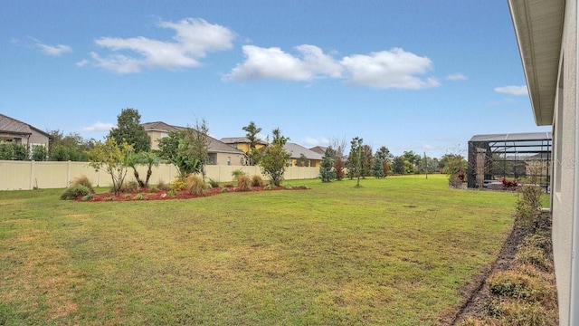 view of yard featuring glass enclosure and fence