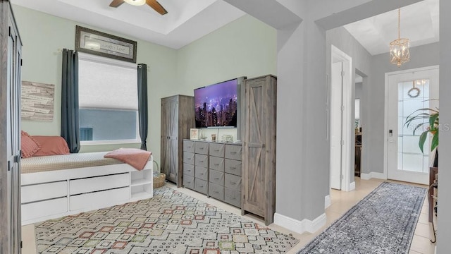 bedroom with ceiling fan with notable chandelier and baseboards