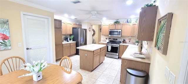 kitchen featuring stainless steel appliances, visible vents, light countertops, ornamental molding, and a center island