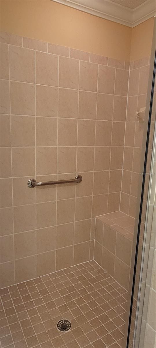 bathroom with ornamental molding and tiled shower