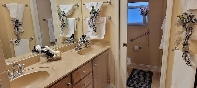 full bathroom featuring double vanity, toilet, a sink, and tile patterned floors