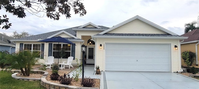 single story home featuring a garage, concrete driveway, and a shingled roof