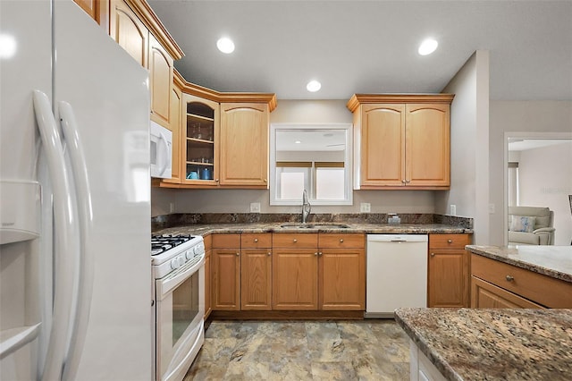 kitchen featuring white appliances, glass insert cabinets, dark stone countertops, a sink, and recessed lighting