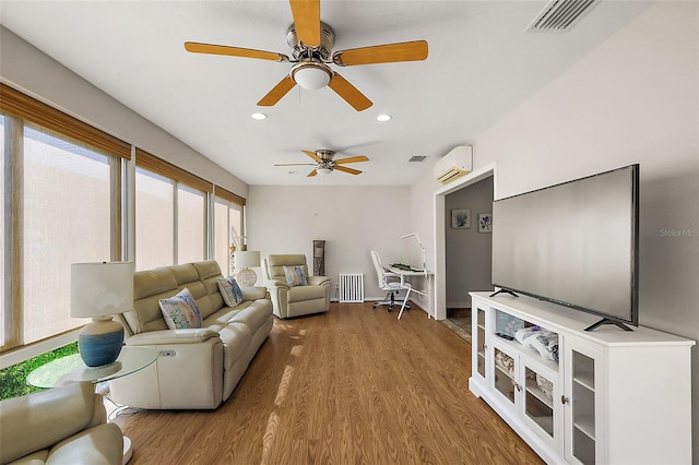 living room with visible vents, a wall unit AC, radiator heating unit, wood finished floors, and recessed lighting