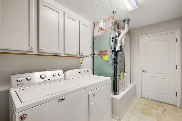 washroom featuring a textured ceiling, washing machine and dryer, baseboards, cabinet space, and heating unit