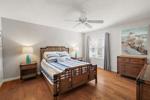 bedroom featuring ceiling fan, a textured ceiling, baseboards, and wood finished floors