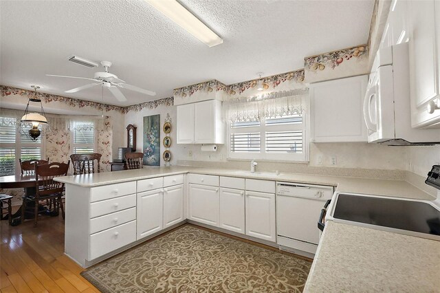 kitchen featuring white appliances, light countertops, a peninsula, and white cabinets