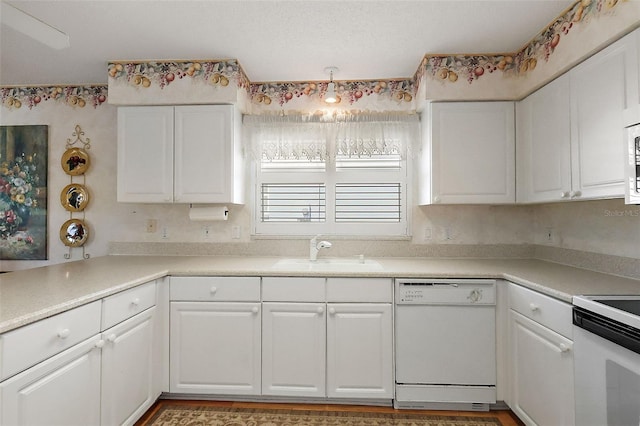 kitchen with light countertops, white appliances, a sink, and white cabinets