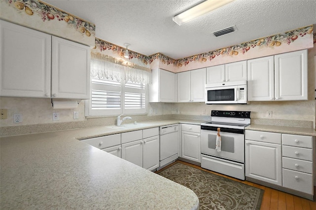 kitchen with a textured ceiling, white appliances, a sink, white cabinetry, and light countertops