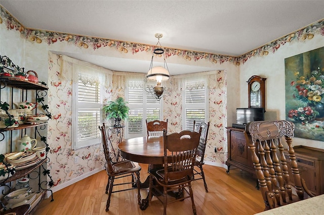 dining area with light wood-style floors, baseboards, and wallpapered walls