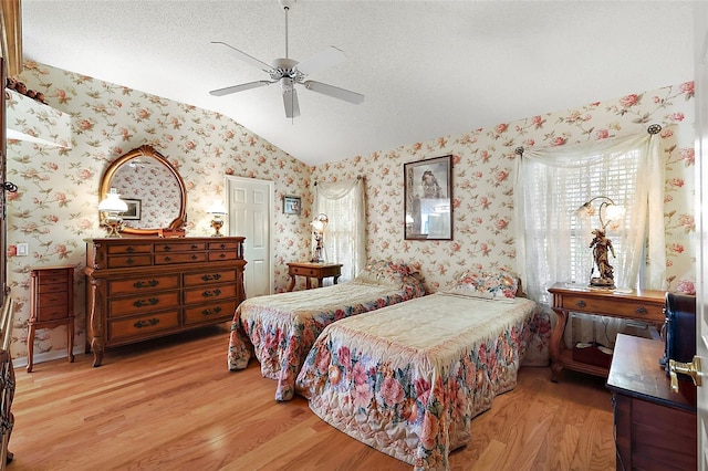 bedroom featuring wood finished floors, vaulted ceiling, and wallpapered walls