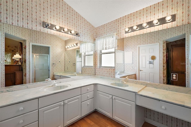 bathroom with vaulted ceiling, a shower stall, vanity, and wallpapered walls