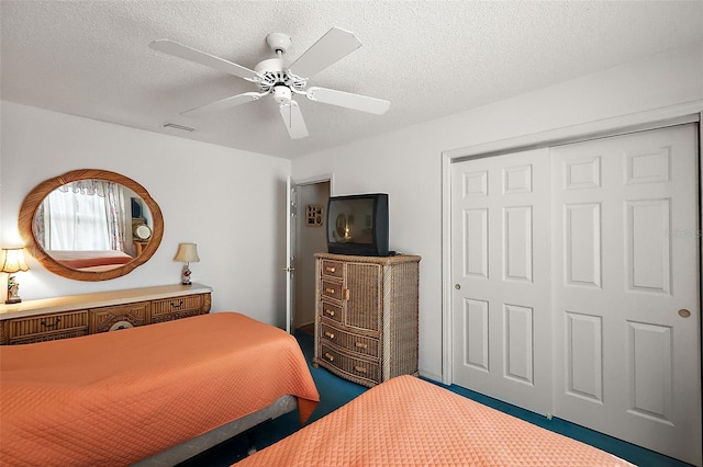 bedroom with carpet floors, visible vents, ceiling fan, and a textured ceiling