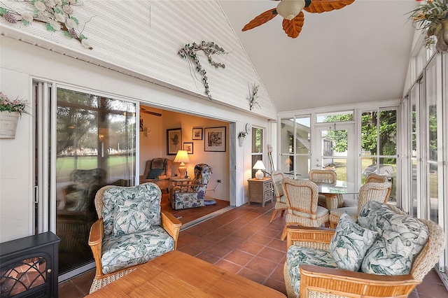 sunroom featuring a wood stove, vaulted ceiling, baseboard heating, and ceiling fan