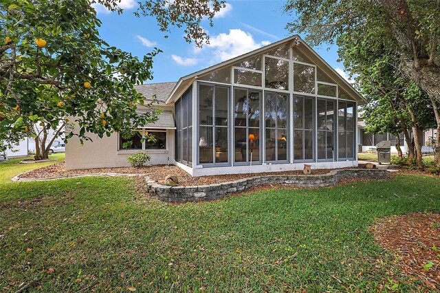 rear view of property with a lawn, a sunroom, and stucco siding