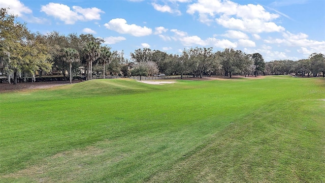 view of property's community with view of golf course and a yard